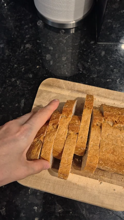 Sliced bread on a wooden cutting board, ready for serving in a kitchen. Stock Footage 334400546