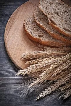 Sliced bread on a wooden cutting board Bundle of wheat and rye ears directly  스톡 사진