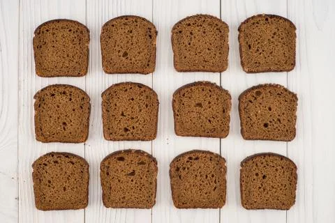 Sliced brown bread on an old white wooden table. Stock Photos