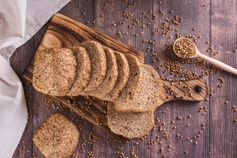 Sliced buckwheat bread on a cutting board and cereals on the table top view Stock Photos