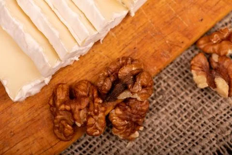 Sliced camembert and walnut kernels on a wooden cutting board, close-up, sele Stock Photos