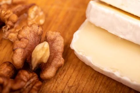 Sliced camembert and walnut kernels on a wooden cutting board, close-up, sele Stock Photos