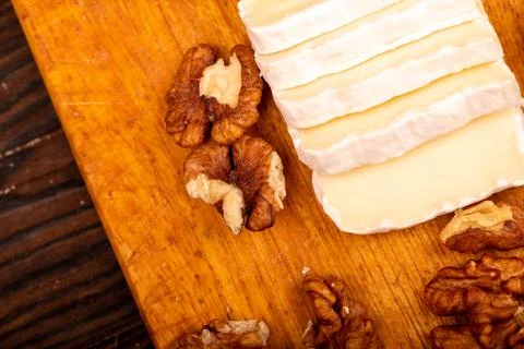 Sliced camembert and walnut kernels on a wooden cutting board, close-up, sele Stock Photos