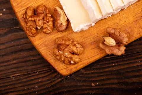 Sliced camembert and walnut kernels on a wooden cutting board, close-up, sele Stock Photos