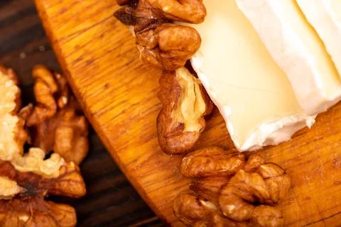 Sliced camembert and walnut kernels on a wooden cutting board, close-up, sele Stock Photos