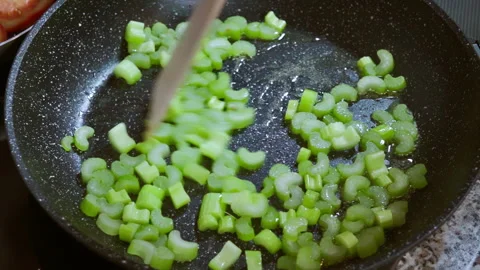 Sliced celery stalks in a frying pan, in hot olive oil. Slow motion100fps. Stock Footage 309300916