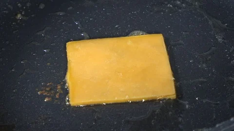 Sliced cheddar melting into a cheese crisp on the stove Stock Footage