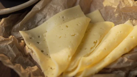 Sliced cheese is on the crafted parchment, cold snacks, natural ingredients Stock Footage 113642378