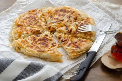 Sliced cheese pastry on the table, next to the turkish tea. Stock Photos