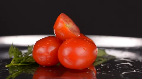 Sliced cherry tomato rotating on metal plate and black background Stock Footage 65227778