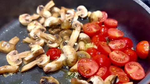 Sliced cherry tomatoes and mushrooms sizzling with steam in frying pan Stock Footage 340296775