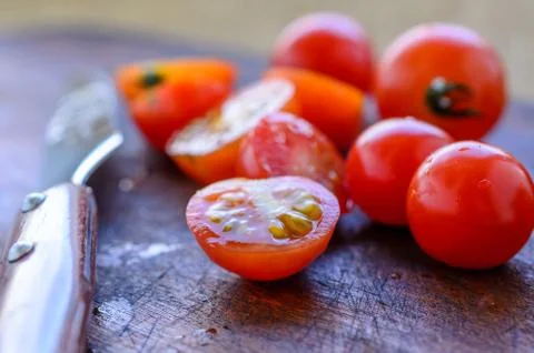Sliced cherry tomatoes and a sharp knife with a wooden handle Stock Photos