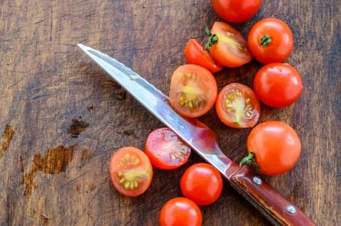 Sliced cherry tomatoes and a sharp knife with a wooden handle Stock Photos