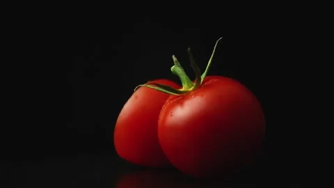 Sliced cherry tomatoes rotate on a black background Stock Footage 163303188