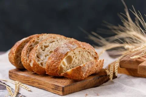 Sliced craft bread on a board close-up on a dark background. The concept of h Stock Photos