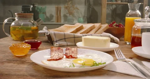 Sliced crunchy bread jumping out of toaster with fried eggs and bacon on Stock Footage 180676476