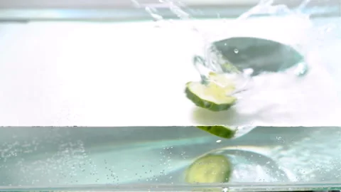 Sliced cucumbers fall into the water Stock Footage 100269782
