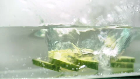 Sliced cucumbers fall into the water Stock Footage 100269813