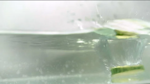Sliced cucumbers fall into the water Stock Footage 100269892