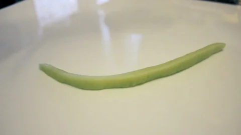 Sliced cucumbers falling down on glass. Cucumbers sliced in long pieces. Stock Footage 125783124