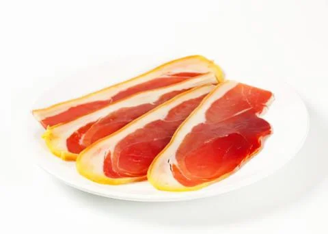 Sliced cured ham on a white plate Stock Photos