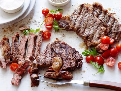 Sliced deep fried beef with tomatoes and herbs on the table Stock Photos