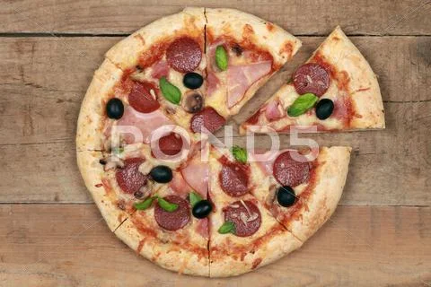 Sliced deluxe pizza on a wooden table Stock Photos