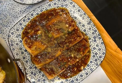 Sliced flatbread with brown sauce and nuts on a blue and white plate. Stock Photos