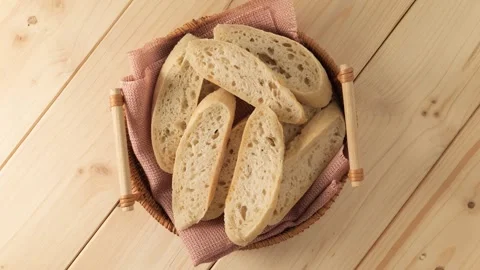 Sliced fresh bread in basket rotating on wooden table Stock Footage 339366913