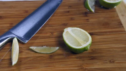 Sliced fresh half lime and segments thrown onto a wooden chopping board Stock Footage 88509778