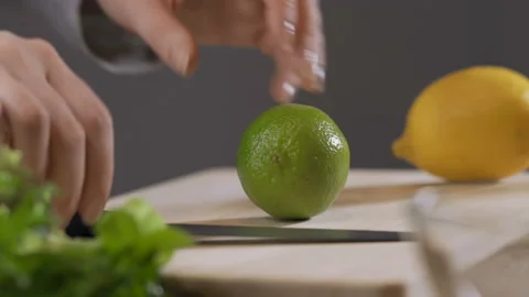 Sliced fresh half lime cut with sharp knife blade using a womans hand onto a Stock Footage 90800165