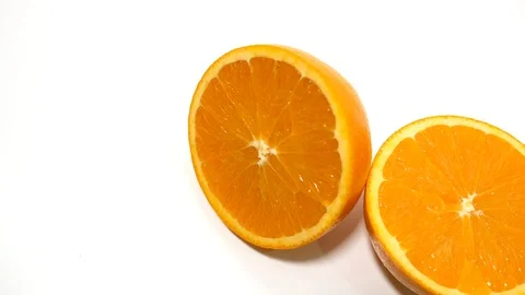 Sliced fresh orange cut in half on white background, overhead view, pan right Stock Footage 99260110
