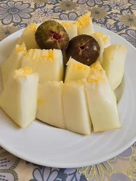 Sliced fresh yellow melon with two figs on a white plate. Stock-Fotos