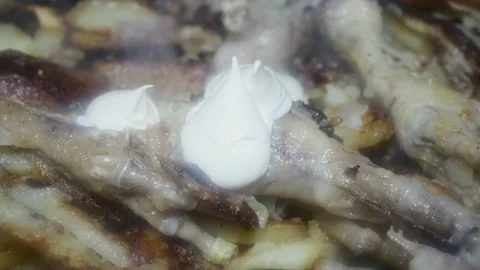 Sliced fried potatoes with clawed chicken legs and mayonnaise in a frying pa Vidéo 227437488