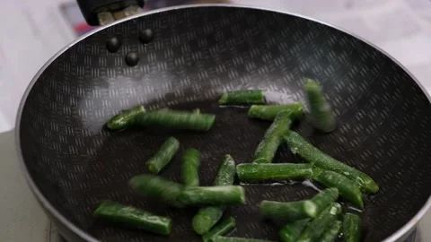 Sliced frozen green string beans fall on a hot frying pan with oil. close-up. Stock Footage 174557591