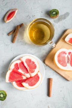 Sliced grapefruit, kiwi fruit, cinnamon, tea Stock Photos