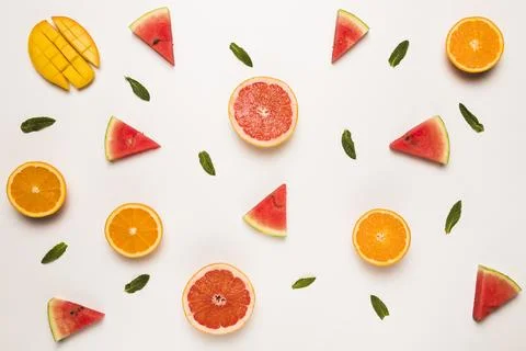 Sliced grapefruit watermelon orange mango green leaves Stock Photos