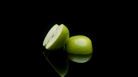 A sliced green apple rotating on a black background 動画素材 128721824