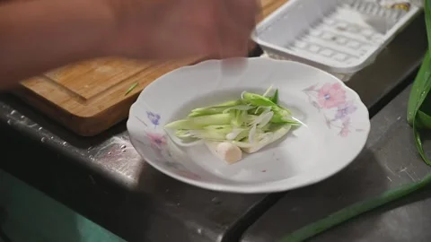 Sliced Green Garlic Sprouts Transferred to a White Ceramic Plate Video stock 346487227