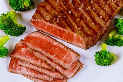 Sliced grilled roasted beef with broccoli on white plate. Stock Photos