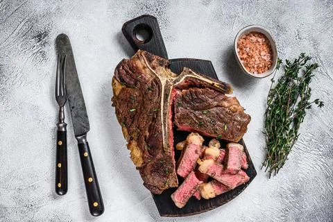 Sliced Grilled T-bone beef meat Steak on a wooden cutting board. White Stock Photos