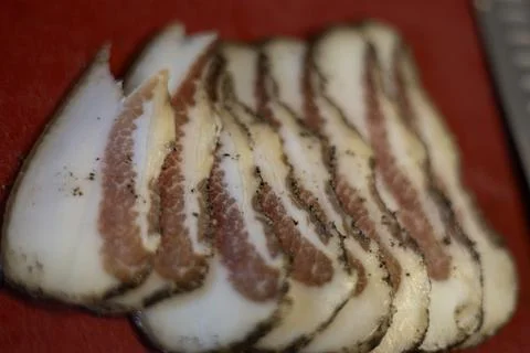 Sliced guanciale with pepper on a red surface Foto stock