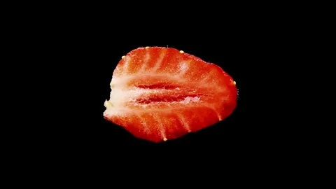 The sliced half of a strawberry rotates on a black background. Stock Footage 244234450