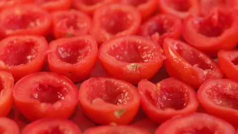 Sliced halves of ripe fresh red tomatoes lie on a baking sheet. Process of Stockbeeldmateriaal 212948779