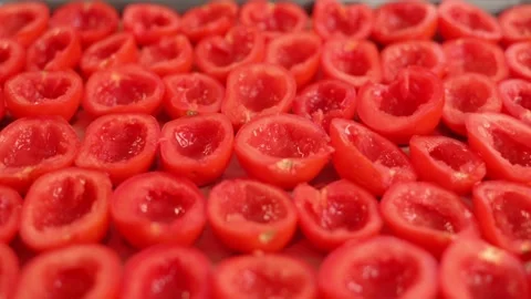 Sliced halves of ripe fresh red tomatoes lie on a baking sheet. Process of Stockbeeldmateriaal 212948891