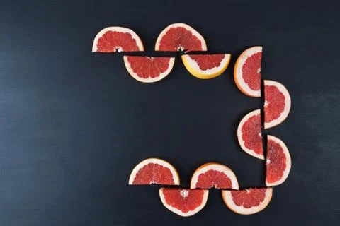 Sliced halvs of red grapefruit on black with copy space Stock Photos