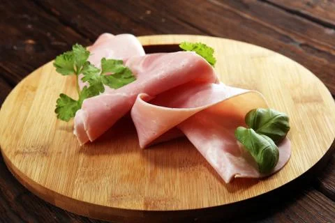 Sliced ham with parsley on table. Fresh prosciutto. Pork ham sliced. Stock Photos