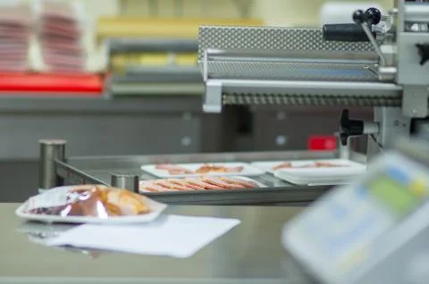 Sliced ham in plastic box and slice machine in supermarket Stock Photos