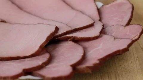 Sliced ham rotating on a wooden table Stock Footage 60928732