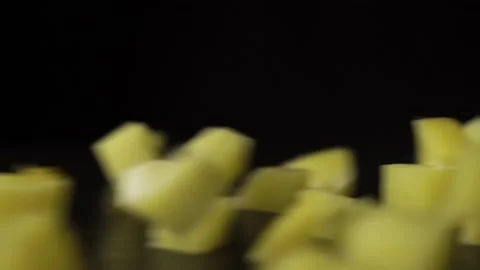 Sliced hard cheese cubes fall from top to bottom on wooden table scatter Stock Footage 144044287